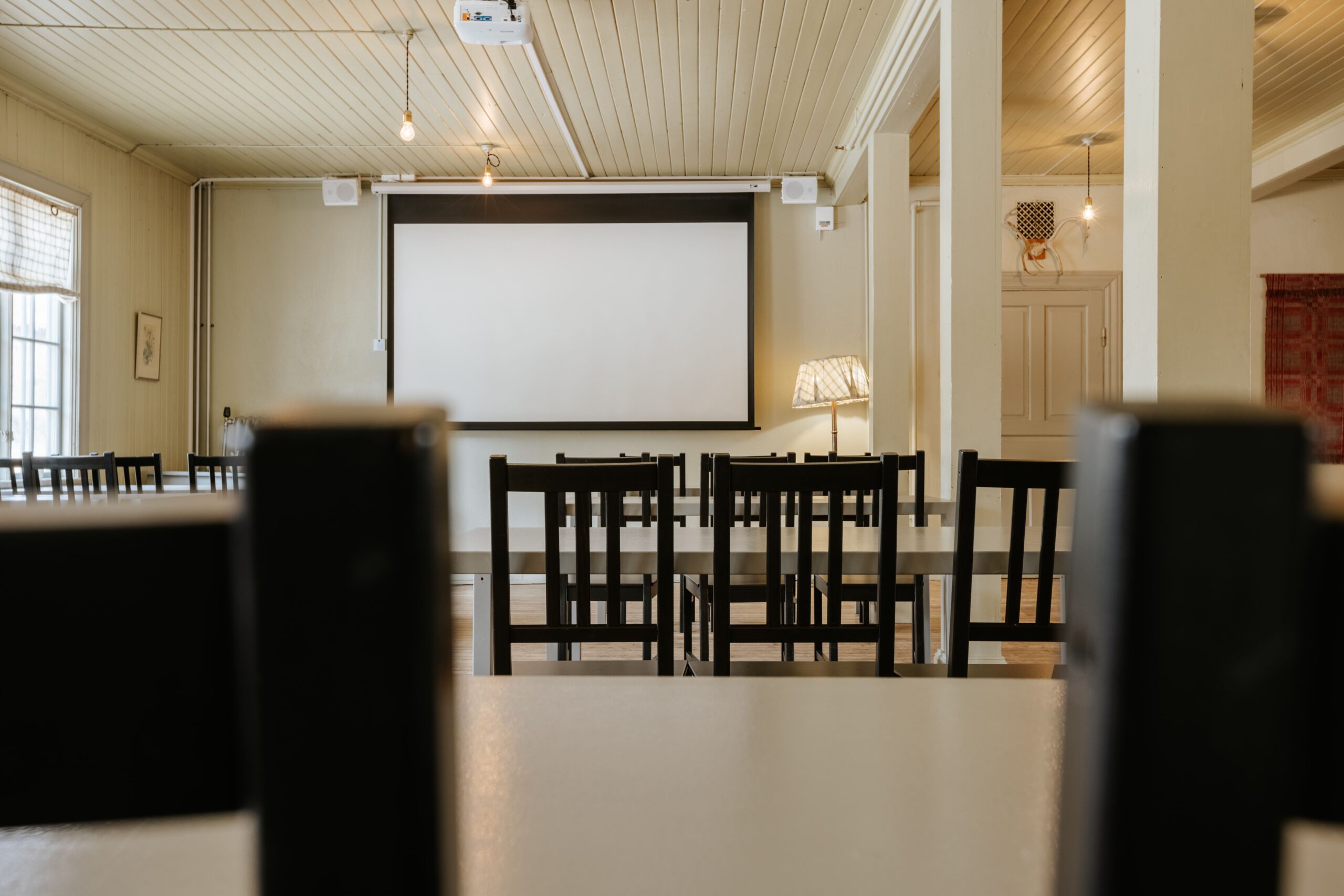 Konferensrum med svartvita stolar och projektion på vägg, i en ljus och luftig miljö. Perfekt för möten.