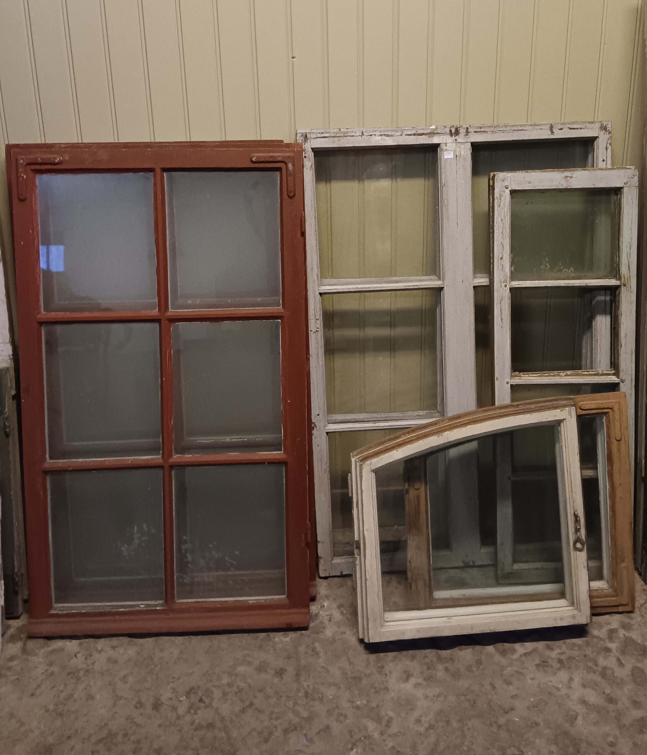 Various old wooden windows in different styles and colors, including red and white, displayed against a light yellow background.